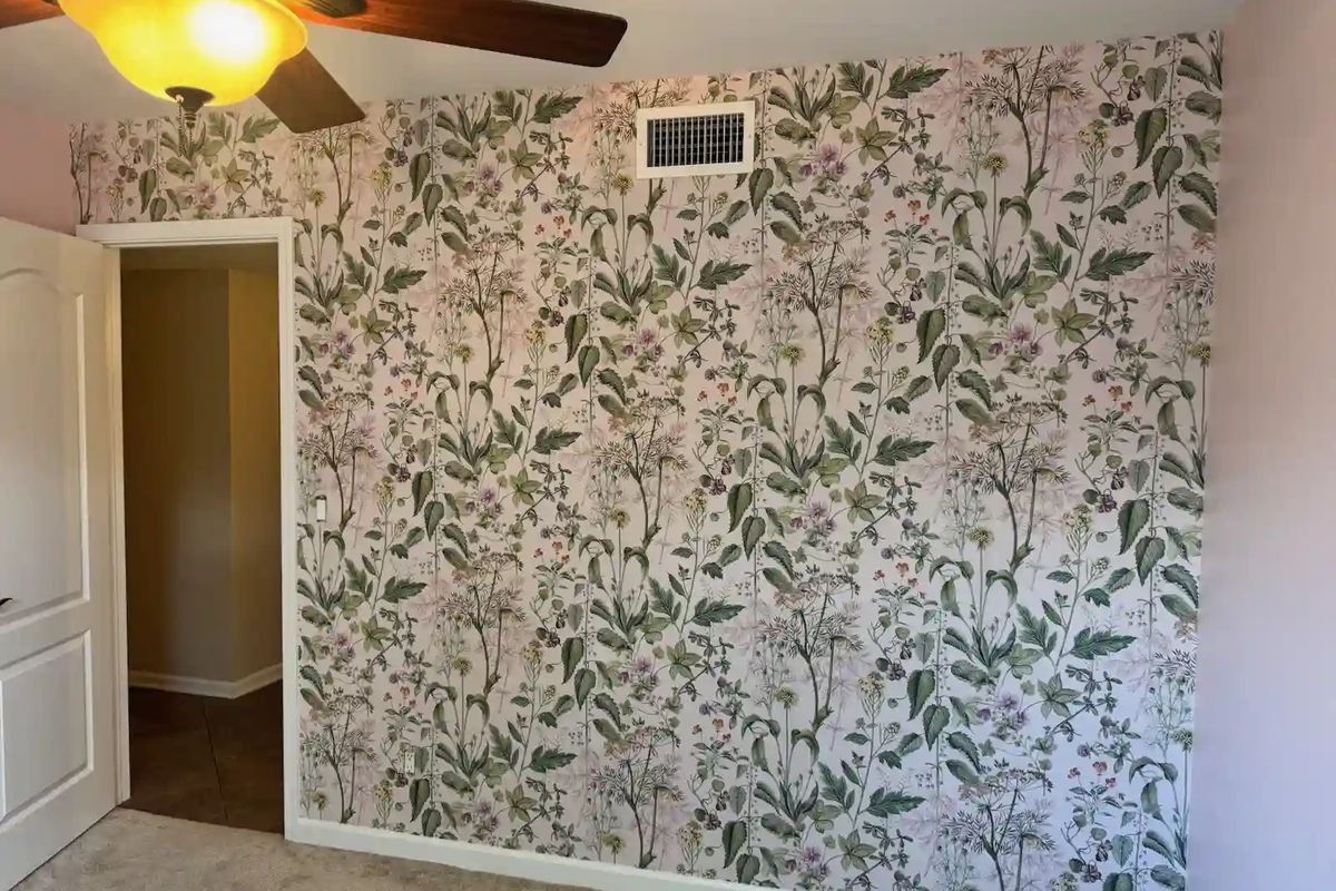 Bedroom wall in a botanical print with green leaves and pale pink flowers