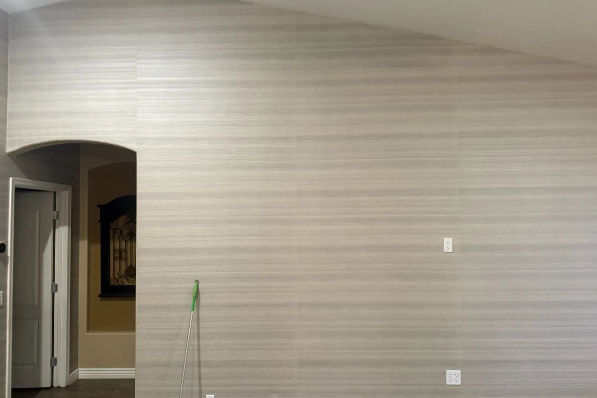 Large wall in a pale, horizontally textured linen-look wallcovering with an arched doorway
