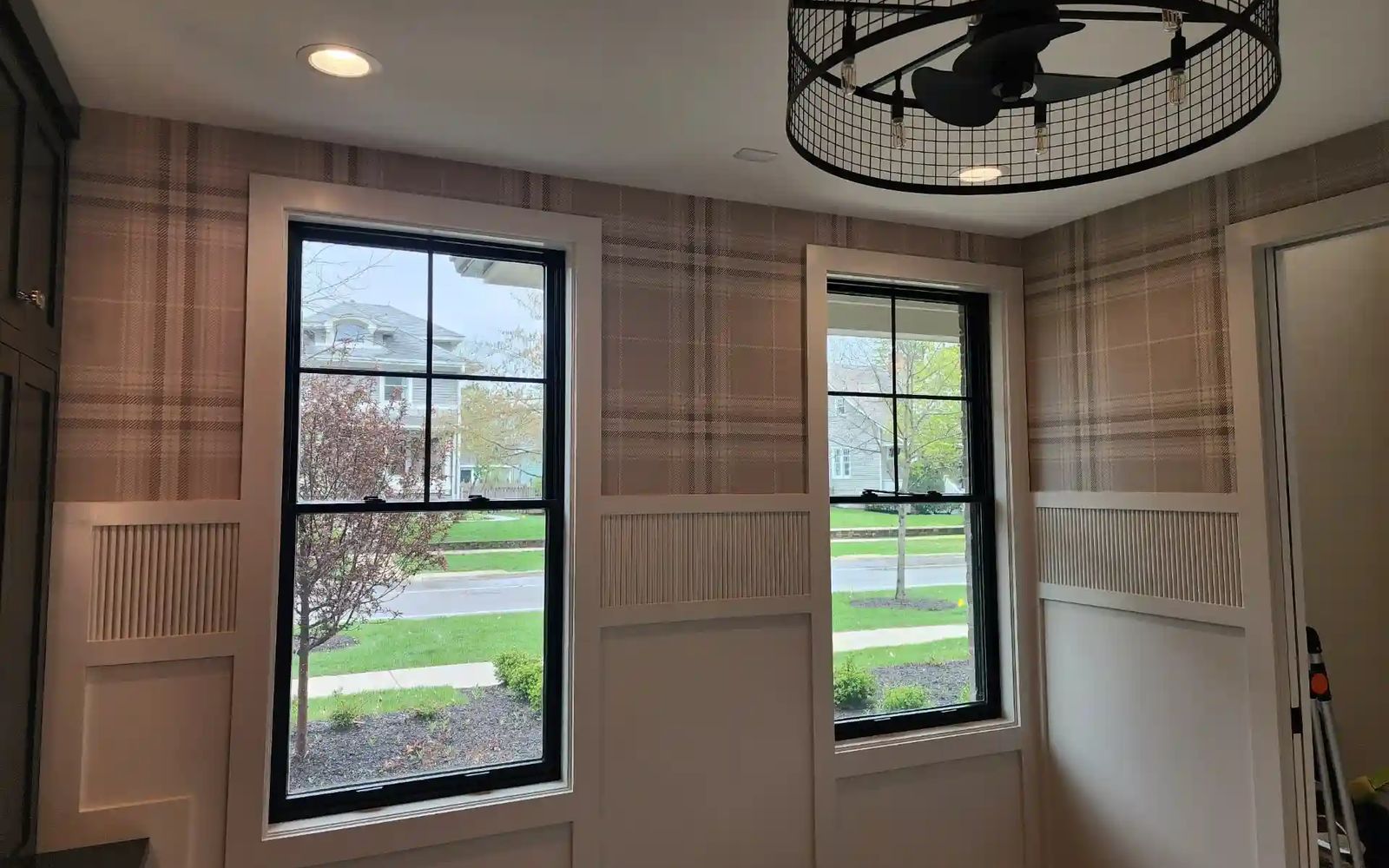 Small study with soft plaid wallpaper, white board-and-batten panels and black-framed windows