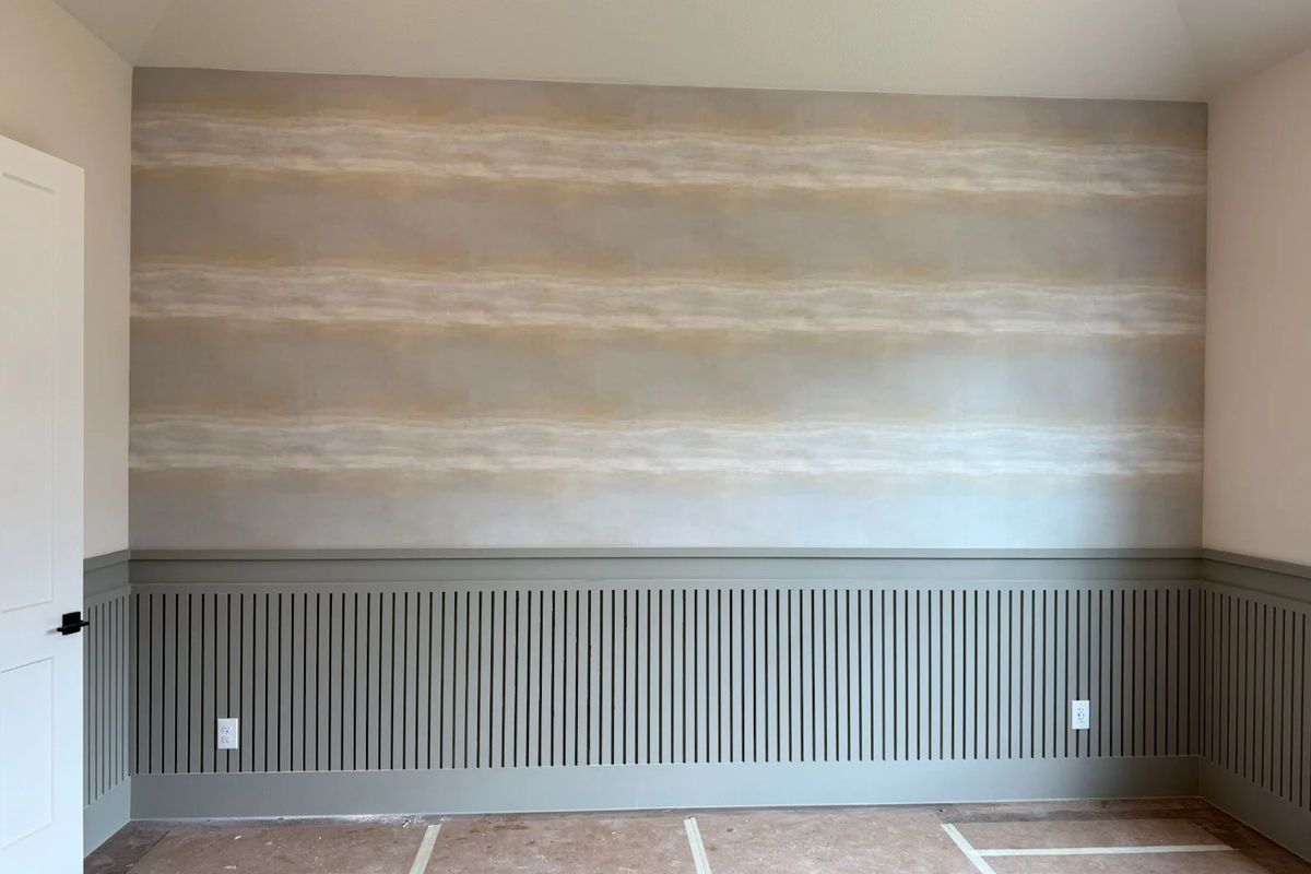 Wall with a soft cream and tan striped wallpaper above a sage-green slatted wainscot, floor still protected