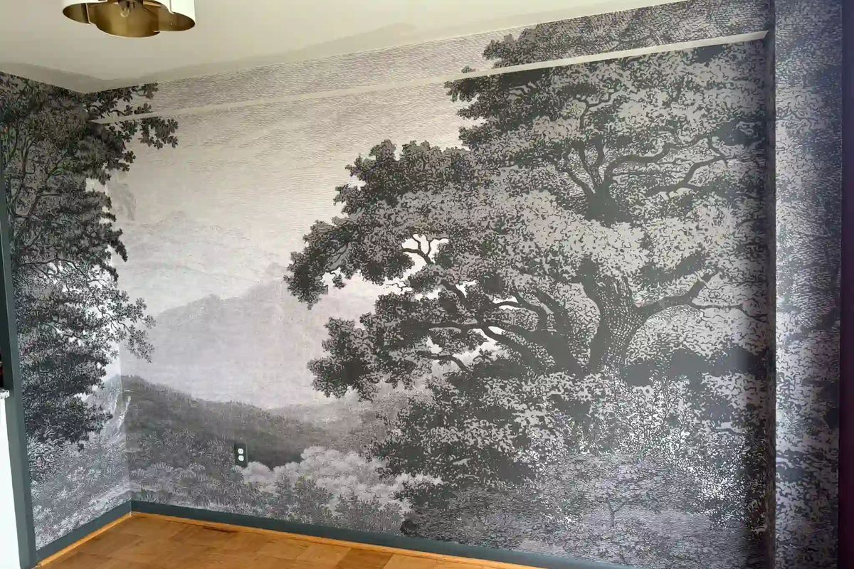 Black-and-white landscape mural of a large spreading tree covering a room wall